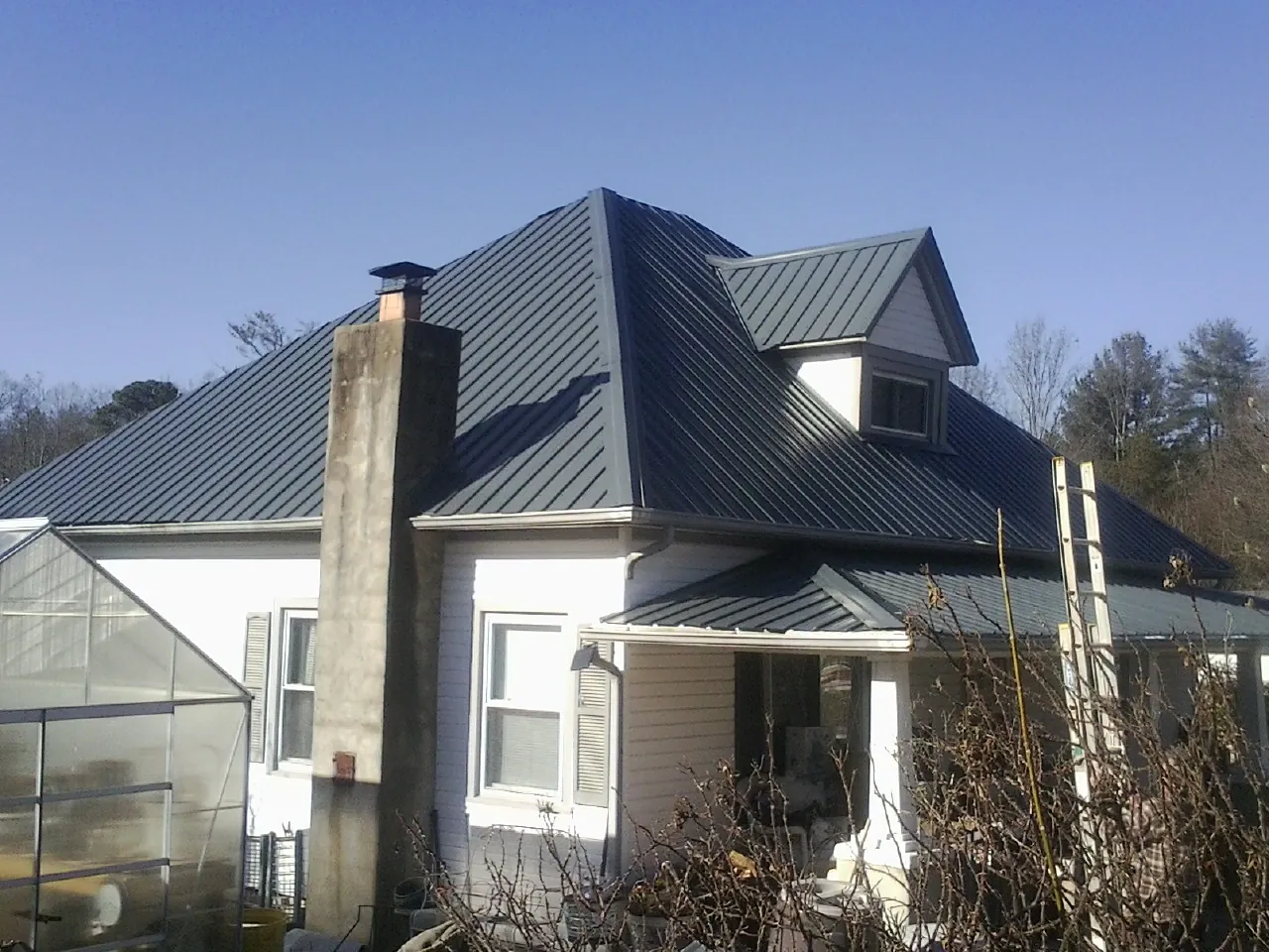 Dark blue standing seam metal roof on a white farmhouse with dormer — Slate & Tile Roof Repair by Roofing Brothers in Upper Sandusky