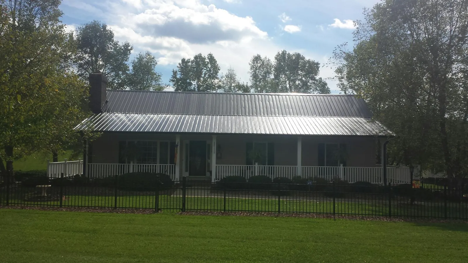 Gray metal roof on a brick ranch with a full width front porch — Gutter Guard Installation work by our crew in Upper Sandusky