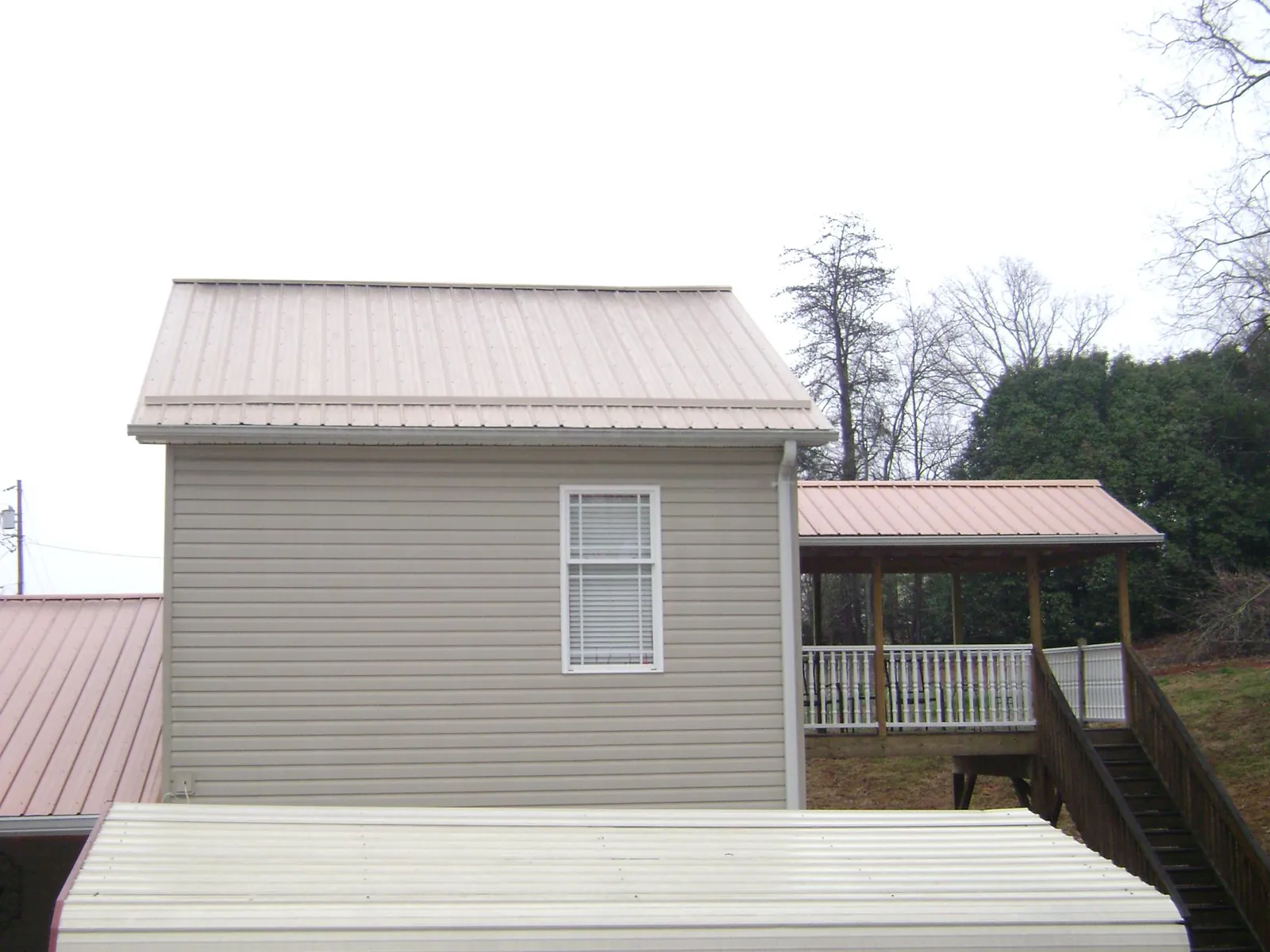 Tan metal roofs on a two story addition and attached porch, from a Roof Replacement job in Upper Sandusky