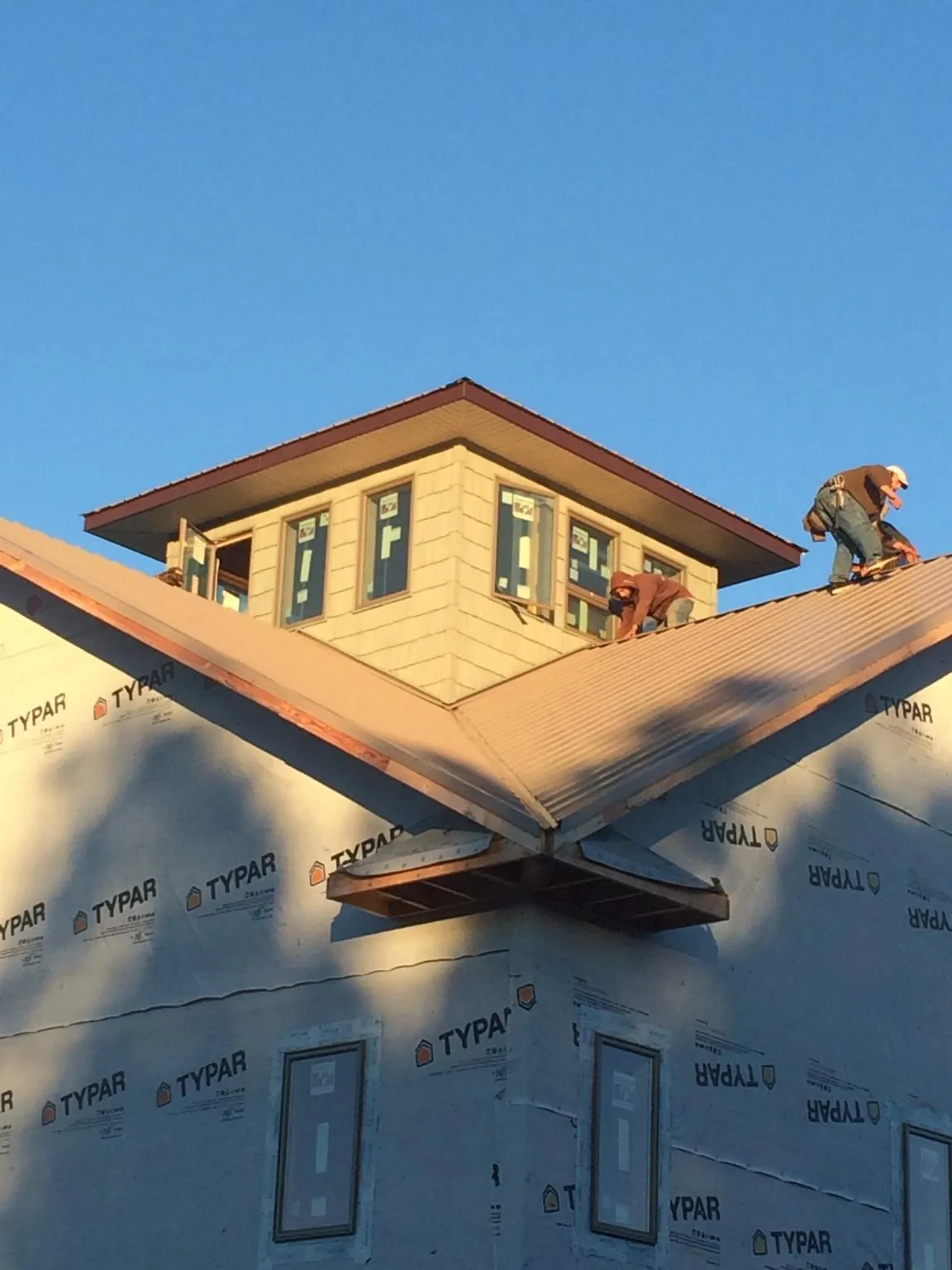 Roofers working around a rooftop cupola on a new metal roof at sunset — Roof Waterproofing in Upper Sandusky by Roofing Brothers